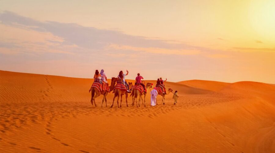 Camel riders silhouetted against a vibrant sunset over the desert near Sharm El Sheikh, creating a dramatic and picturesque scene