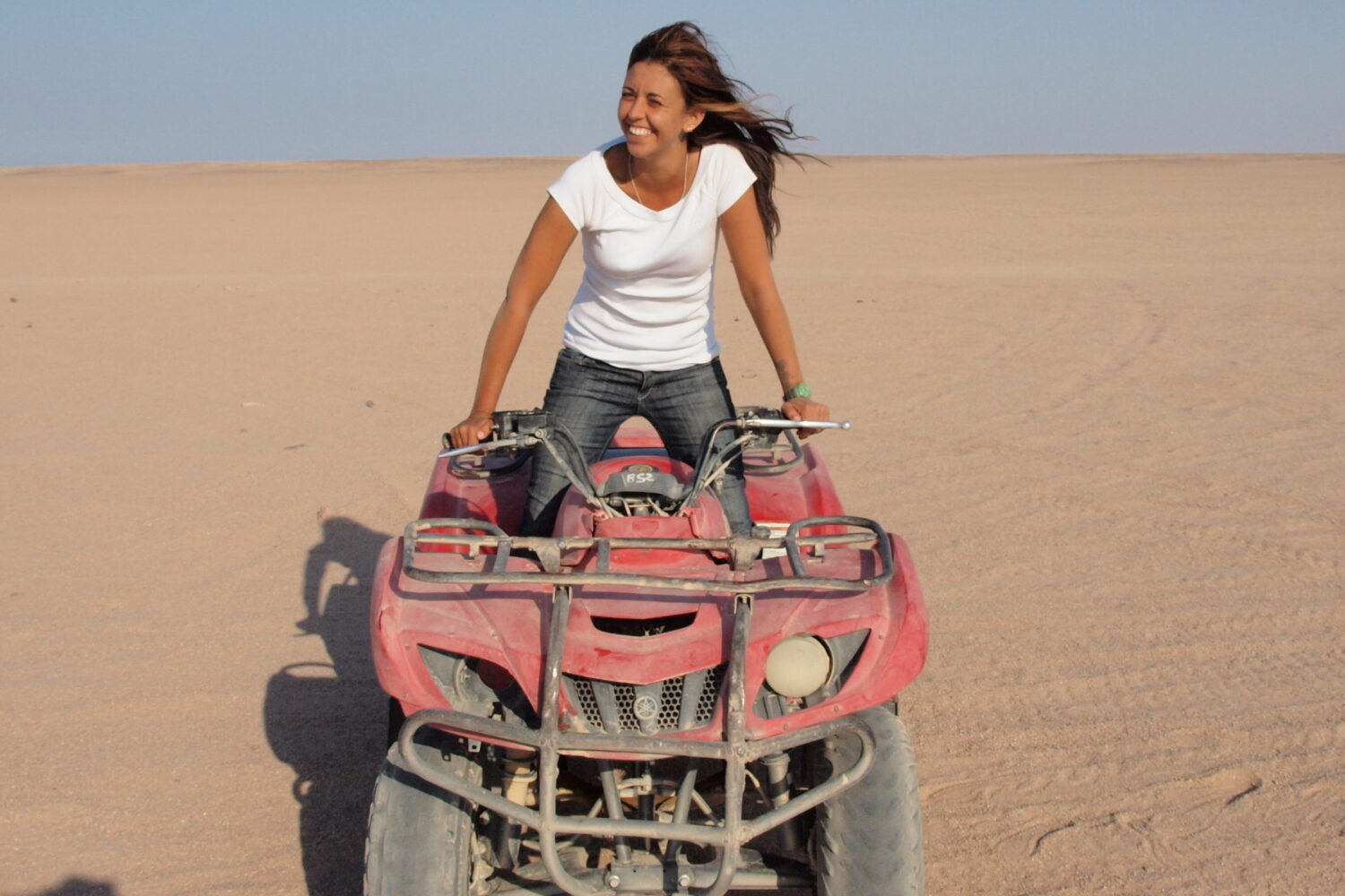Un touriste souriant sur un quad, traversant le désert à toute vitesse