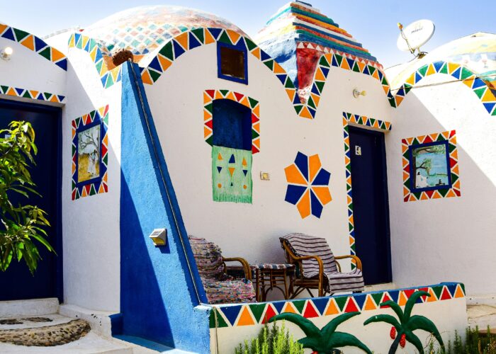 A peaceful Nubian Village nestled by the serene waters of the Nile River in Aswan, with traditional felucca boats nearby