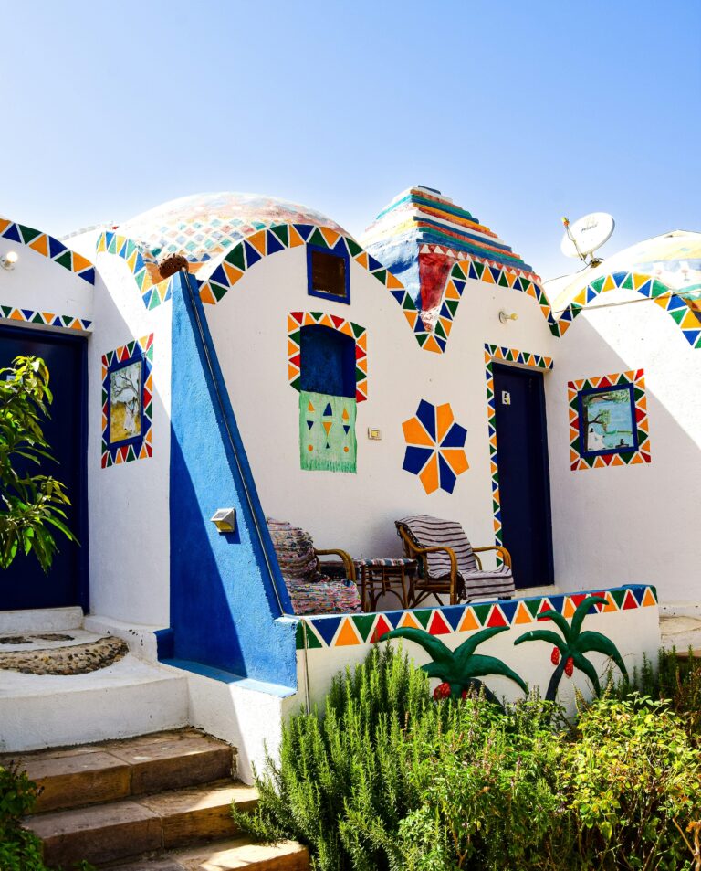 A peaceful Nubian Village nestled by the serene waters of the Nile River in Aswan, with traditional felucca boats nearby