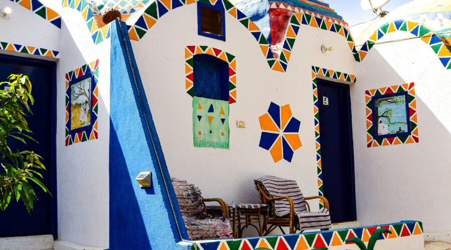 A peaceful Nubian Village nestled by the serene waters of the Nile River in Aswan, with traditional felucca boats nearby