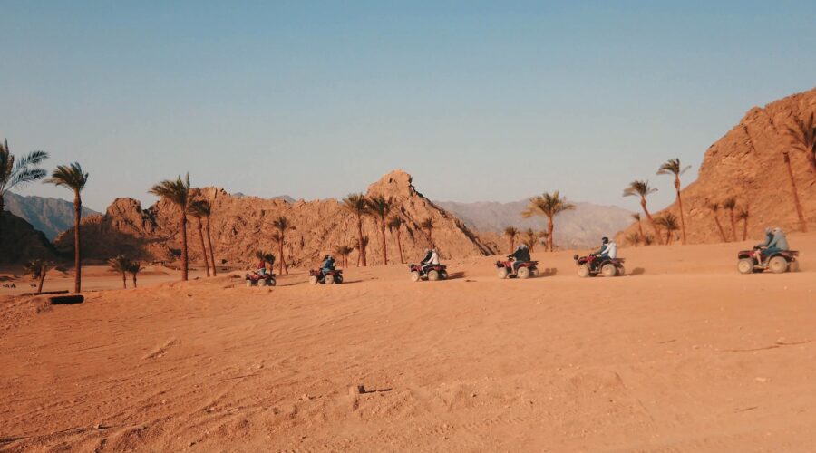 A group of people on quad bikes navigating a desert trail near Hurghada